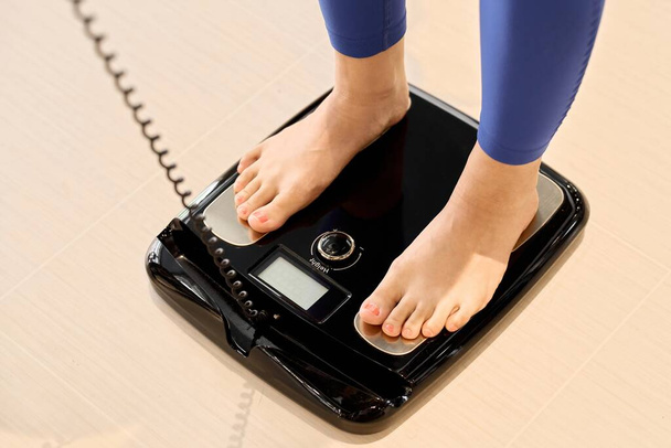 Una mujer que usa una escala de grasa corporal en el gimnasio - Foto, Imagen