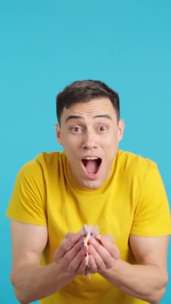 Video van lachende man blazen confetti op blauwe chroma key achtergrond - Video