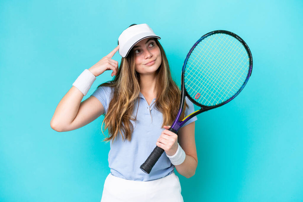 Joven jugadora de tenis aislada sobre fondo azul teniendo dudas y pensando - Foto, imagen