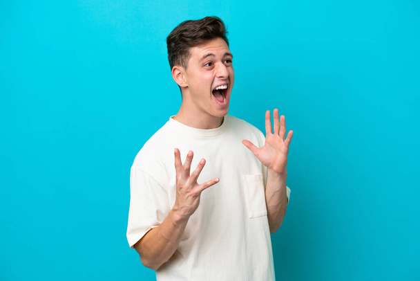 Young handsome Brazilian man isolated on blue background with surprise facial expression - Photo, Image