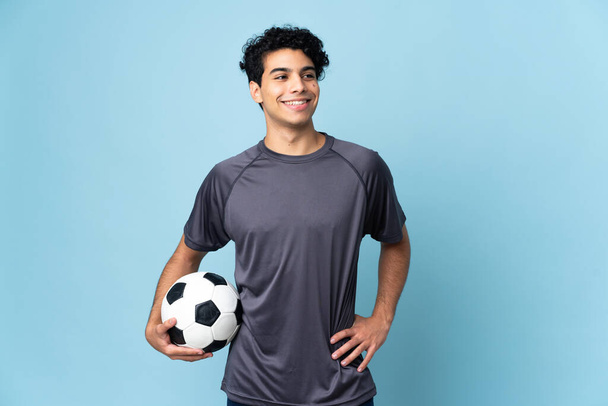 Venezuelan football player man over isolated background posing with arms at hip and smiling - Photo, Image