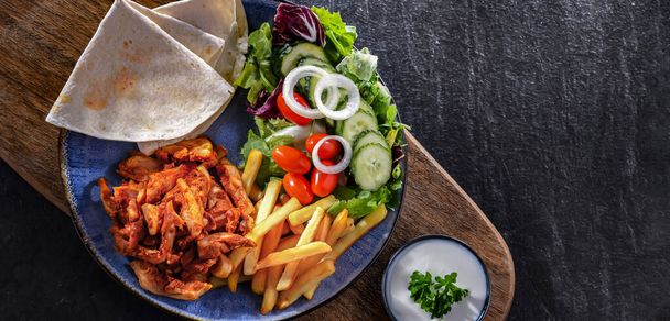 Kebab podávaný s hranolky, pitta chlebem, zeleninou a tzatziki - Fotografie, Obrázek
