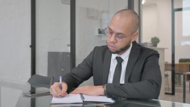 Смешанный расовый бизнесмен пишет бизнес-отчет за работой - Кадры, видео