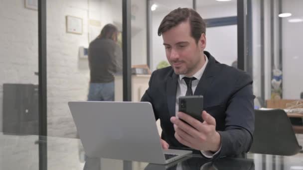 Középkorú üzletember Laptopon dolgozik és okostelefont használ - Felvétel, videó