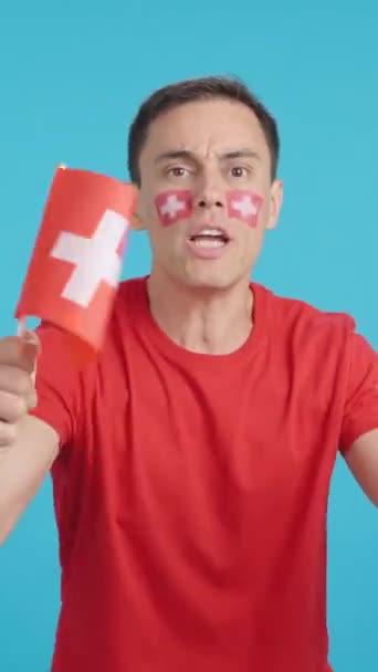 Video ve studiu s chromou muže mávající švýcarskou národní vlajkou naštvaný na rozhodnutí rozhodčích - Záběry, video