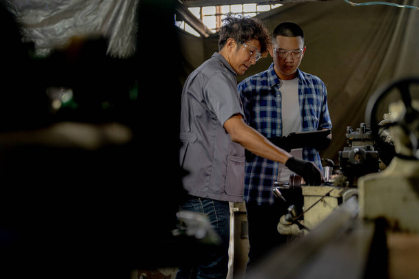 Les hommes inspectent les pièces en acier pour l'installation de la machine. équipe d'enseignants et d'étudiants apprennent à utiliser des machines lourdes dans une aciérie. travailleurs coopèrent lors du contrôle de la qualité des produits manufacturés. - Photo, image