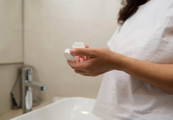 Close-up vrouw handen vasthouden pot met anti veroudering, hydraterende, verjongende cosmetische product serum crème. Huidverzorging concept, Schoonheid en spa - Foto, afbeelding