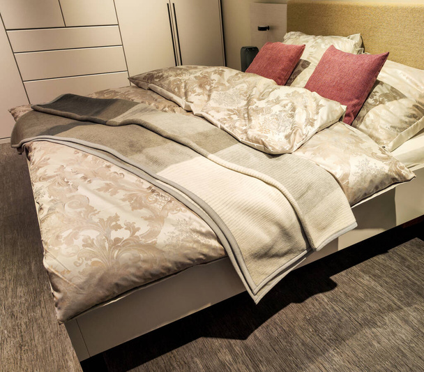 Yastıklı ve battaniyeli rahat ve davetkar bir çift kişilik yatak güzel ışıklandırmalı bir uyku odasında. - Fotoğraf, Görsel