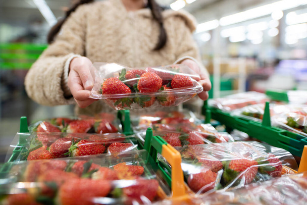 Girl picking up strawberries in a supermarket - Foto, Bild