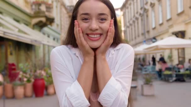 Молода щаслива кавказька жінка насолоджується усміхненою зубною посмішкою веселою задоволеною жінкою, дивлячись на камеру задоволеною моделлю весела дівчинка міська вулиця поза жестом відзначає гарний настрій міський успіх - Кадри, відео