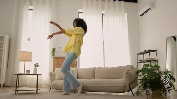 Taniec śmieszne Afroamerykanka młoda piękna kręcone włosy dziewczyna skoków w mieszkaniu etniczne radosne kobieta pani taniec do muzyki szczęśliwe życie ekscytujące dobry nastrój o zabawy wakacje weekend strona domowa - Materiał filmowy, wideo