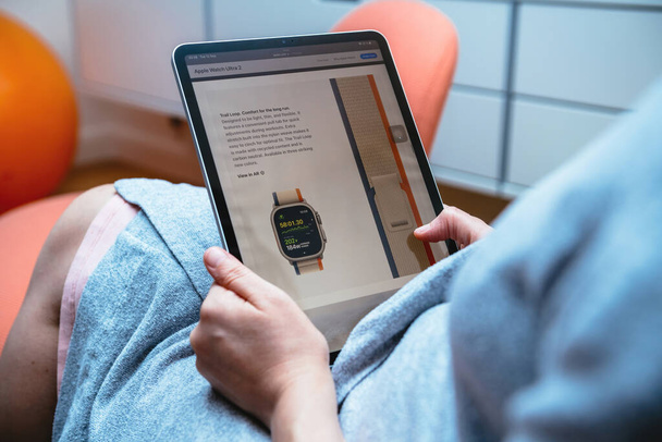 Londra, İngiltere - 13 Eylül 2023: Yeni Apple Watch Ultra 2 'de bir iz döngüsü sergilenirken, bir kadın tabletinde bunu okuyor, teknoloji ve doğayı harmanlıyor. - Fotoğraf, Görsel