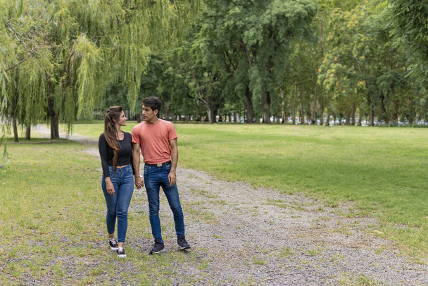 Verliebtes Paar läuft Händchen haltend im Park - Foto, Bild
