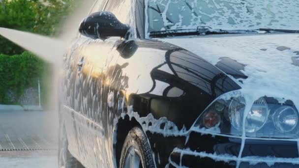 Πλύσιμο πολυτελούς μαύρου αυτοκινήτου σε πλυντήριο αυτοκινήτων χωρίς επαφή. Καθαρίζω τις λεπτομέρειες του αυτοκινήτου. Πλυντήριο sedan αυτοκίνητο με αφρό self-service και νερό υψηλής πίεσης. Καθαριότητα και τάξη στο αστικό περιβάλλον - Πλάνα, βίντεο