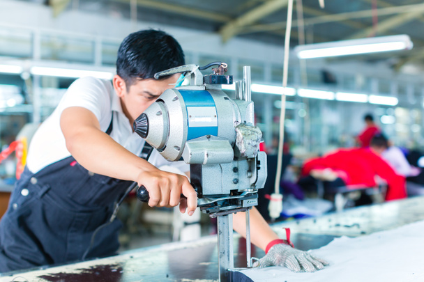 Aziatische werknemer met behulp van een machine in een fabriek - Foto, afbeelding