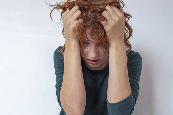 Ένα κορίτσι με κόκκινα μαλλιά κλαίει στο δωμάτιό της. Διαχείριση συναισθημάτων - Φωτογραφία, εικόνα