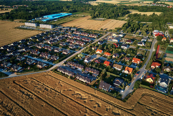 Жилые дома в маленьком городке рядом с сельскохозяйственным полем, вид с высоты птичьего полета. Вид с воздуха на европейский пригородный район с таунхаусами. Недвижимость в Польше - Фото, изображение