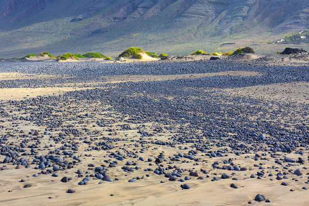 İspanya 'nın Kanarya Adaları' ndaki Lanzarote Adası 'nda çakıl taşı sahili olan volkanik bir arazi. - Fotoğraf, Görsel