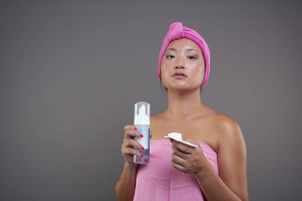 Post-shower skincare ritual of a young Chinese woman, wrapped in towels - Photo, Image