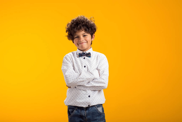 Lächelnder glücklicher Junge im Alter von 6-7 Jahren. Auf gelbem Hintergrund Studio - Foto, Bild