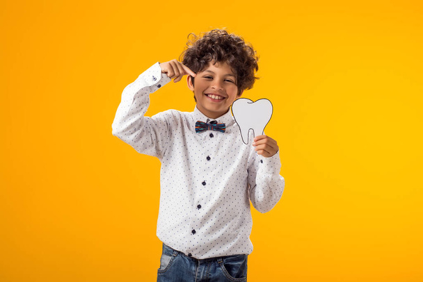Hymyilevä poika, jolla on paperihammas. Hammasterveyden käsite - Valokuva, kuva