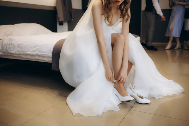 Braut zieht Hochzeitsschuhe an ihren zarten Füßen an. Hochwertiges Foto - Foto, Bild