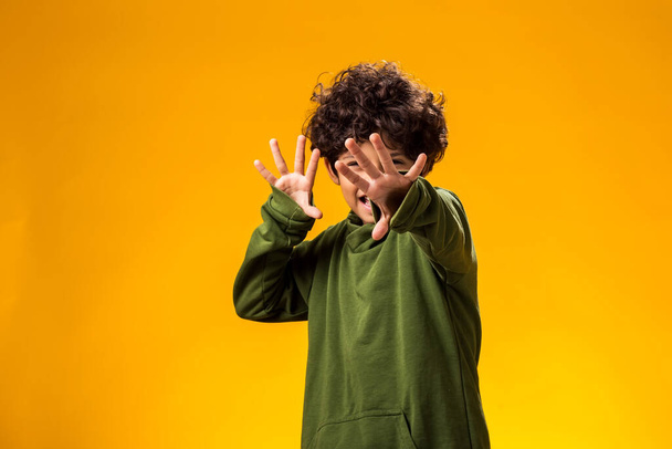 ortrait of afraid child boy showing stop gesture on yellow background. Bulling and negative emotions concept - Photo, Image