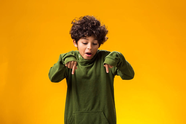 Portret chłopca wskazującego palcem na żółtym tle. Koncepcja emocji dzieci - Zdjęcie, obraz