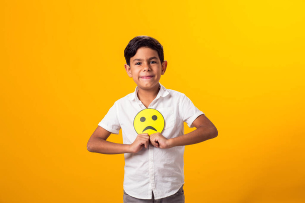 счастливый мальчик держит бумажные смайлики с хорошим и плохим настроением - Фото, изображение