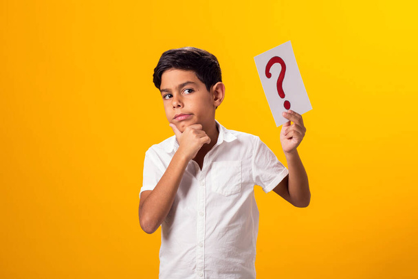 Portret chłopca trzymającego w ręku kartę z pytaniami. Koncepcja edukacji - Zdjęcie, obraz