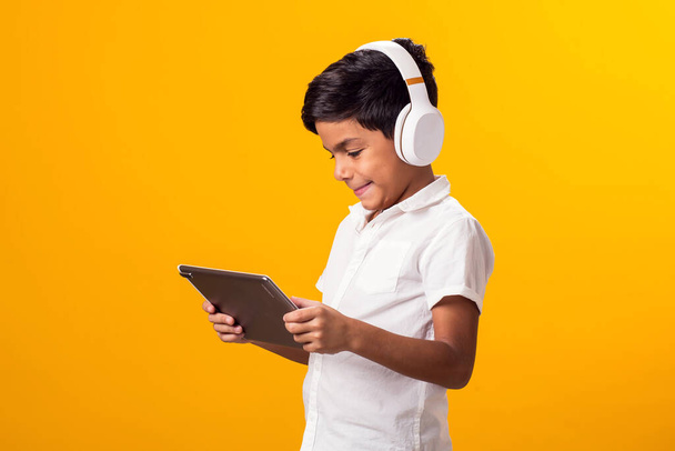 Kulaklık ve tabletle video oyunu oynayan çocuk portresi. Boş zaman ve alet bağımlılığı konsepti - Fotoğraf, Görsel