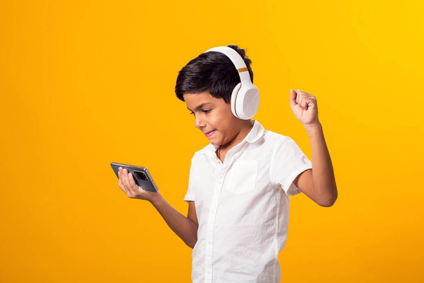 Πορτρέτο του παιδιού αγόρι με ακουστικά και smartphone παίζοντας video game. Έννοια του εθισμού στον ελεύθερο χρόνο και το gadget - Φωτογραφία, εικόνα