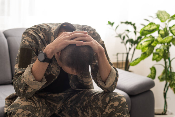 Um soldado perturbado cobrindo seu rosto, possivelmente sofrendo de choque de concha ou transtorno de estresse pós-traumático. Foto de alta qualidade - Foto, Imagem