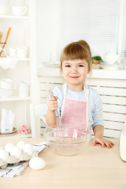 Little girl preparing cookies in kitchen at home - Fotó, kép