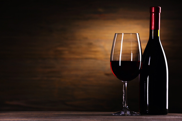 Wineglass and bottle on wooden background - Foto, imagen