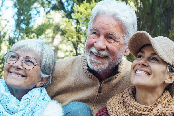 Kaukasische Familienporträt Lächeln und Umarmung mit Naturbäumen Waldhintergrund. Erwachsene und erwachsene Rentner genießen gemeinsam Freizeitaktivitäten im Freien. Konzept für Urlaub in den Bergen - Foto, Bild
