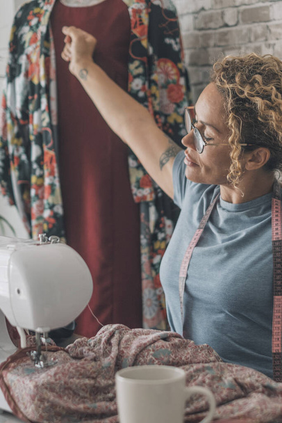 Жінка розтягує руки після роботи над швейною машиною вдома або дизайнерською студією одягу. Жіноче розтягування тіла після перевтоми з репарацією одягу або виробництва. Концепція альтернативної роботи в приміщенні
 - Фото, зображення