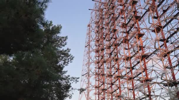 Zoom out Sistema radar Duga vista attraverso gli alberi con cielo blu sullo sfondo a Chernobyl, Ucraina. Filmati 4k di alta qualità - Filmati, video