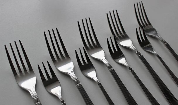 Los tenedores de mesa y los tenedores de pastel se colocan en orden uno tras otro en blanco - Foto, Imagen