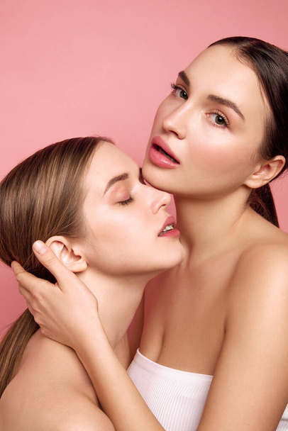 Authentic Allure. Girls illuminate power of unity. Fashion portrait of two pretty women with bare shoulders posing against pink studio background. Concept of cosmetic products, make-up. Ad - Photo, Image