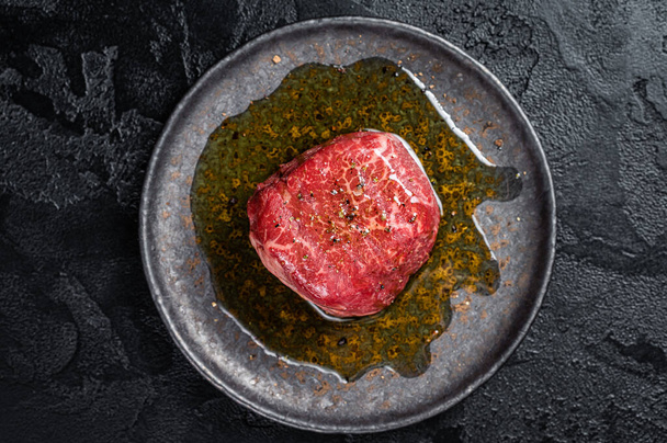 Fillet Mignon prime beef steak, raw dry aged marble meat with herbs and spices ready for cooking. Black background. Top view. - Foto, immagini
