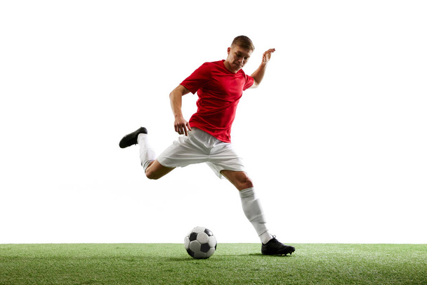 動きの精度について。 熟練したサッカー選手は,緑の草で白い背景に対して比類のない精度を示し,完璧な空中パスを提供します. スポーツのコンセプト,ワールドカップシーズン,試合 - 写真・画像