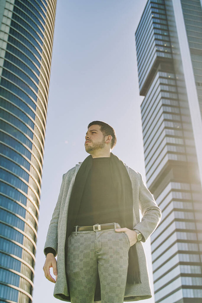 элегантный молодой латиноамериканский бизнесмен позирует с офисными зданиями на заднем плане. пространство для копирования текста. - Фото, изображение