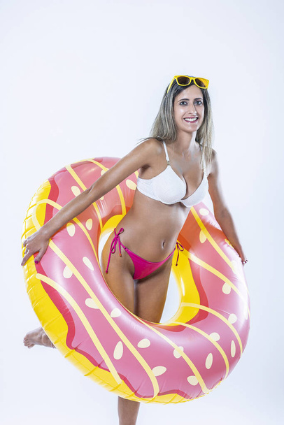 Frau im Bikini mit großem aufblasbaren Schwimmring vor grauem Hintergrund. - Foto, Bild