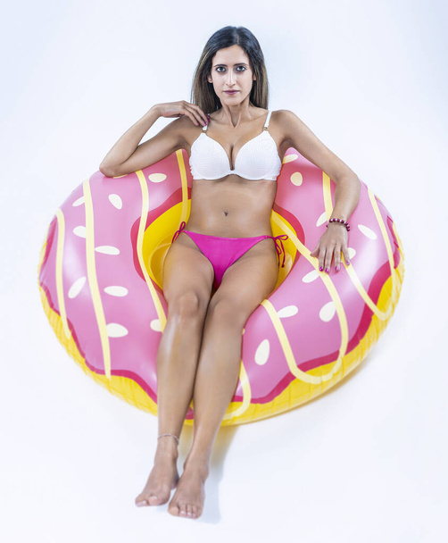 Gri arkaplanı üzerinde şişme yüzme halkası olan bikinili bir kadın.. - Fotoğraf, Görsel