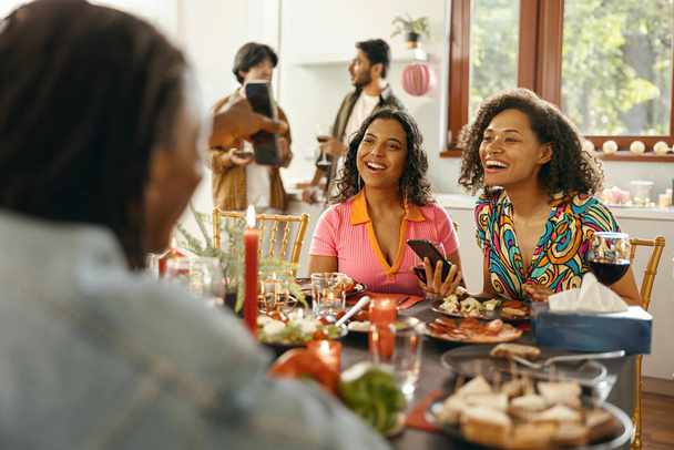 Groupe d'amis souriants profiter de la conversation et boire du vin pendant la fête de Noël à la maison - Photo, image