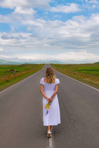 Дівчина в білій сукні стоїть на дорозі. Високоякісна фотографія - Фото, зображення