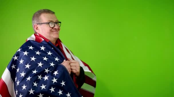A fekete öltönyös és szemüveges idősebb férfi a győzelem jeleként emeli fel az amerikai zászlót. Az idős ember öltönyben és kalapban a függetlenség nemzeti zászlaját lengeti július 4-én. Zöld képernyő, krómkulcs. - Felvétel, videó