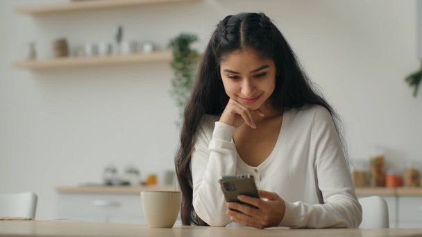 Millennial Smartphone-Nutzer arabische Frau tippt Nachricht in häuslicher Küche weibliche Hausbesitzer Mädchen mit Handy Online-App bestellen Essenslieferservice auf dem Handy surfen Koch-Website - Foto, Bild