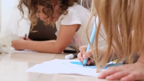 Sevimli küçük çocuklar yerde yatar ve renkli kalemlerle çizerler. - Video, Çekim